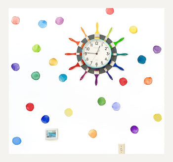 Art classrooom wall is adorned with watercolor dots and features a clock decorated with rainbow paintbrushes. 