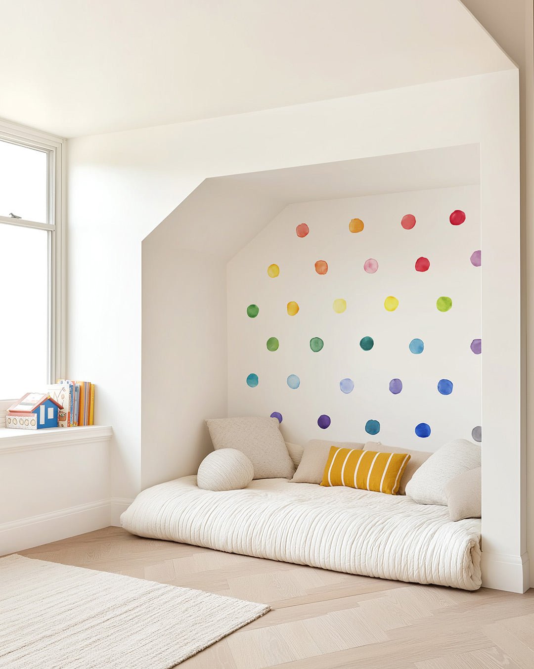 Kids play space with a low modern bed in front of a wall of watercolor rainbow dots.