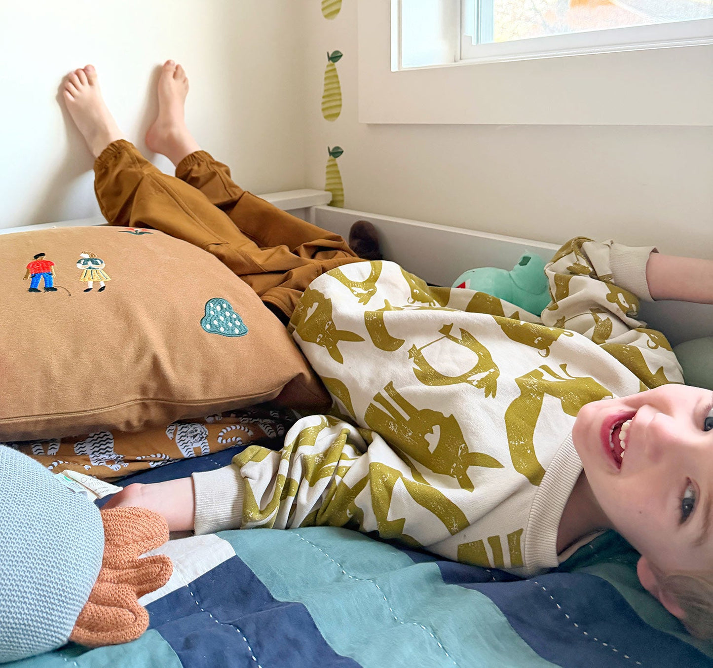 Happy boy playing on top bunk in a shared kids room.
