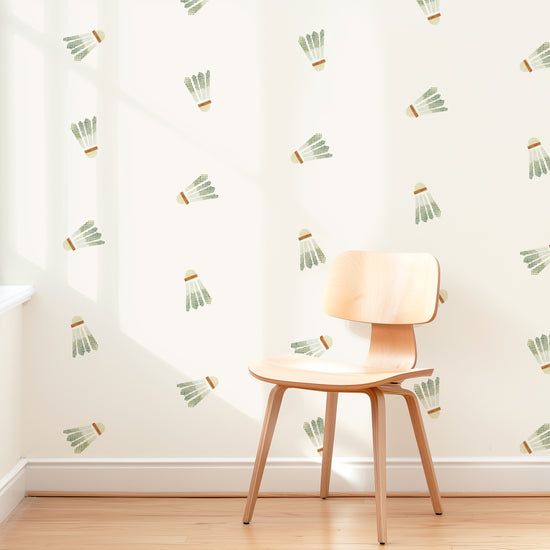 A wall is decorated with watercolor badminton birdie removable fabric wall decals by Mej Mej. They are placed in a grid pattern. A modern chair sits in front of them for scale.