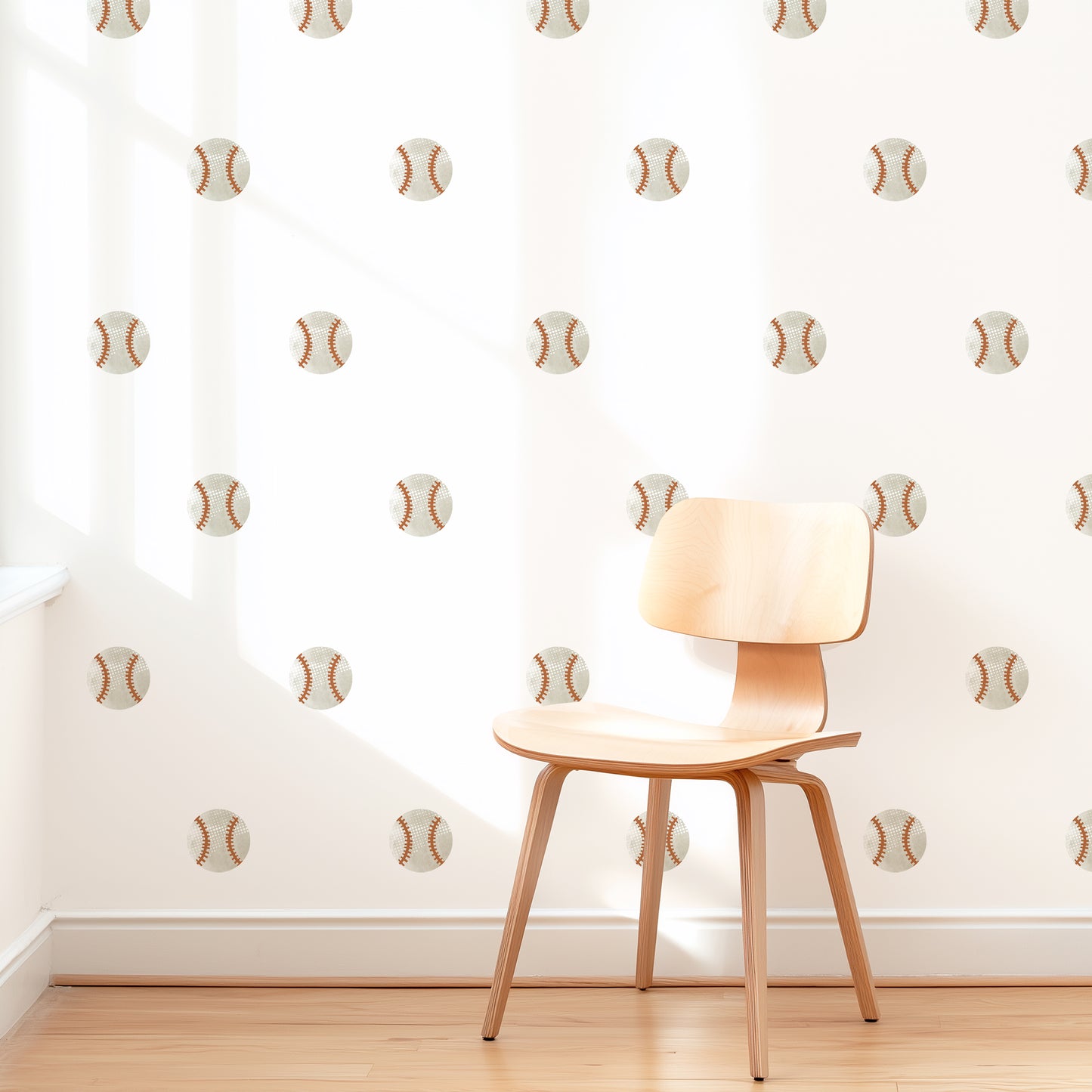 A wall is decorated with watercolor baseball removable fabric wall decals by Mej Mej. They are placed in a grid pattern. A modern chair sits in front of them for scale.