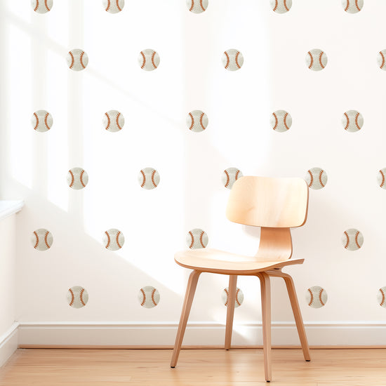 A wall is decorated with watercolor baseball removable fabric wall decals by Mej Mej. They are placed in a grid pattern. A modern chair sits in front of them for scale.