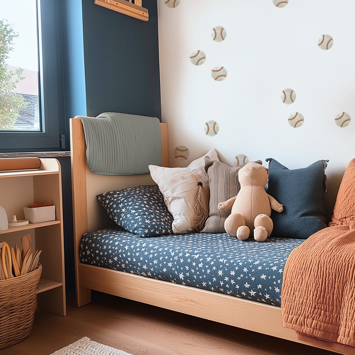 Watercolor baseball wall decals by Mej Mej are the accent wall behind a modern twin bed with navy sheets, muted orange quilt and coordinated pillows in a kids’ room.