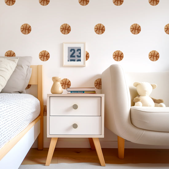 A teen room wall adorned with watercolor basketball wall decals by Mej Mej is the background for a modern chest, bed and chair. The decals are placed in an even pattern behind a small framed basketball jersey number 23.