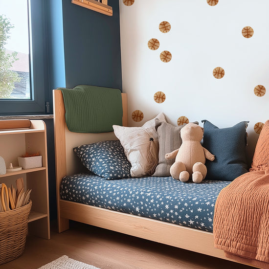 Watercolor basketball wall decals by Mej Mej are the accent wall behind a modern twin bed with navy sheets, muted orange quilt and coordinated pillows in a kids’ room.