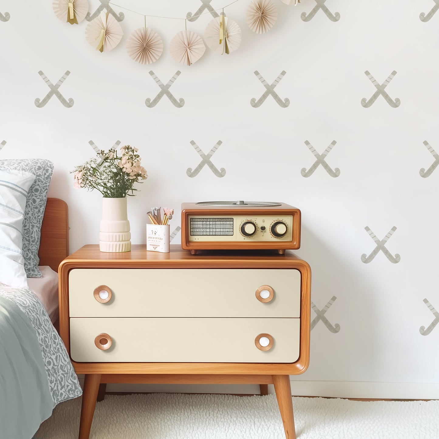 A tween room features wall decals with muted watercolor crossed field hockey sticks by Mej Mej. A vintage chest and radio are styled for a modern look.