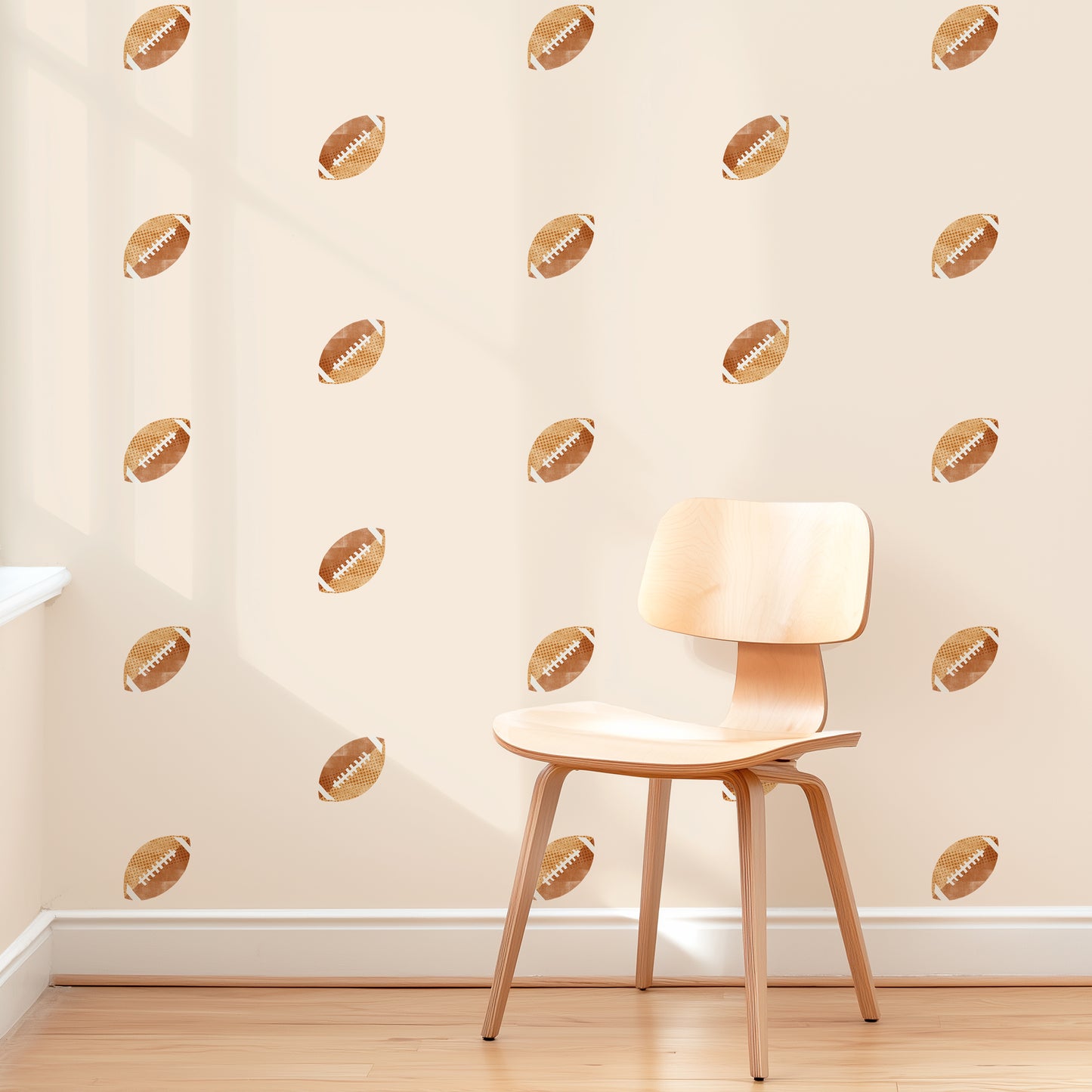 A wall is decorated with watercolor football removable fabric wall decals by Mej Mej. They are placed in a grid pattern. A modern chair sits in front of them for scale.