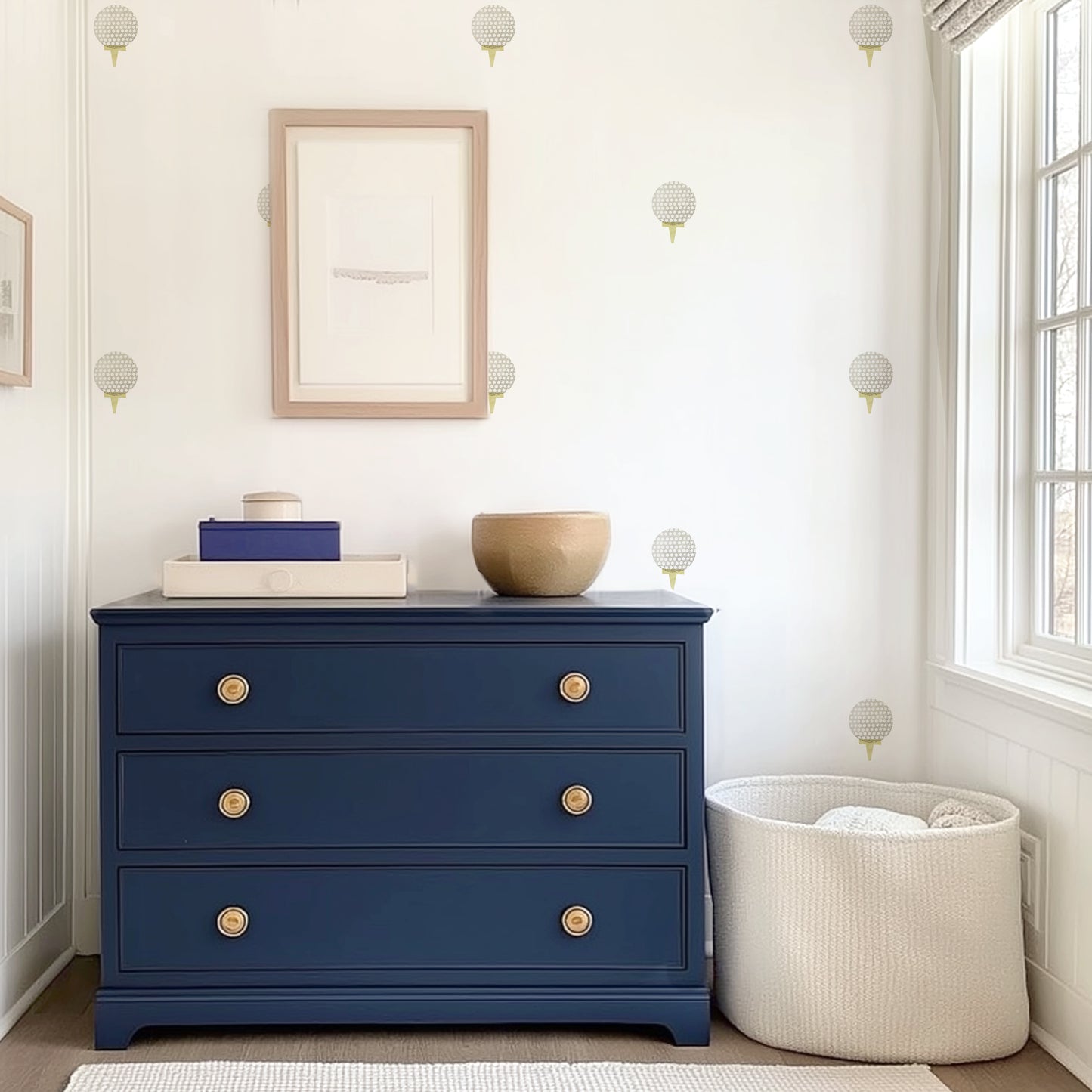 Watercolor golf ball removable decals by Mej Mej are placed in an open grid on an accent wall in a dressing area behind a navy chest of drawers and basket of blankets.