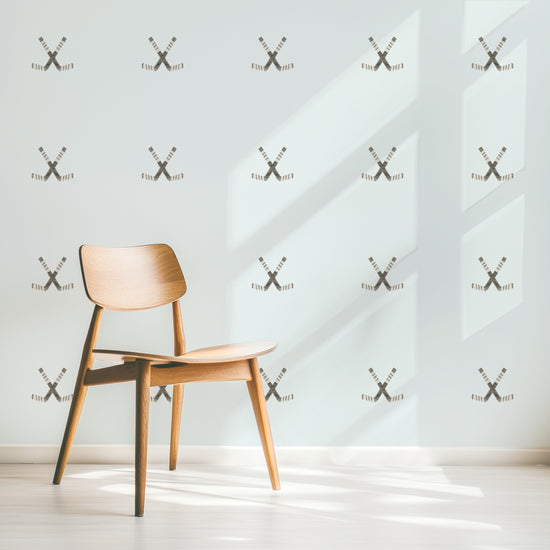 A wall is decorated with watercolor crossed hockey sticks removable fabric wall decals by Mej Mej. They are placed in a modern grid pattern. A modern chair sits in front of them for scale.