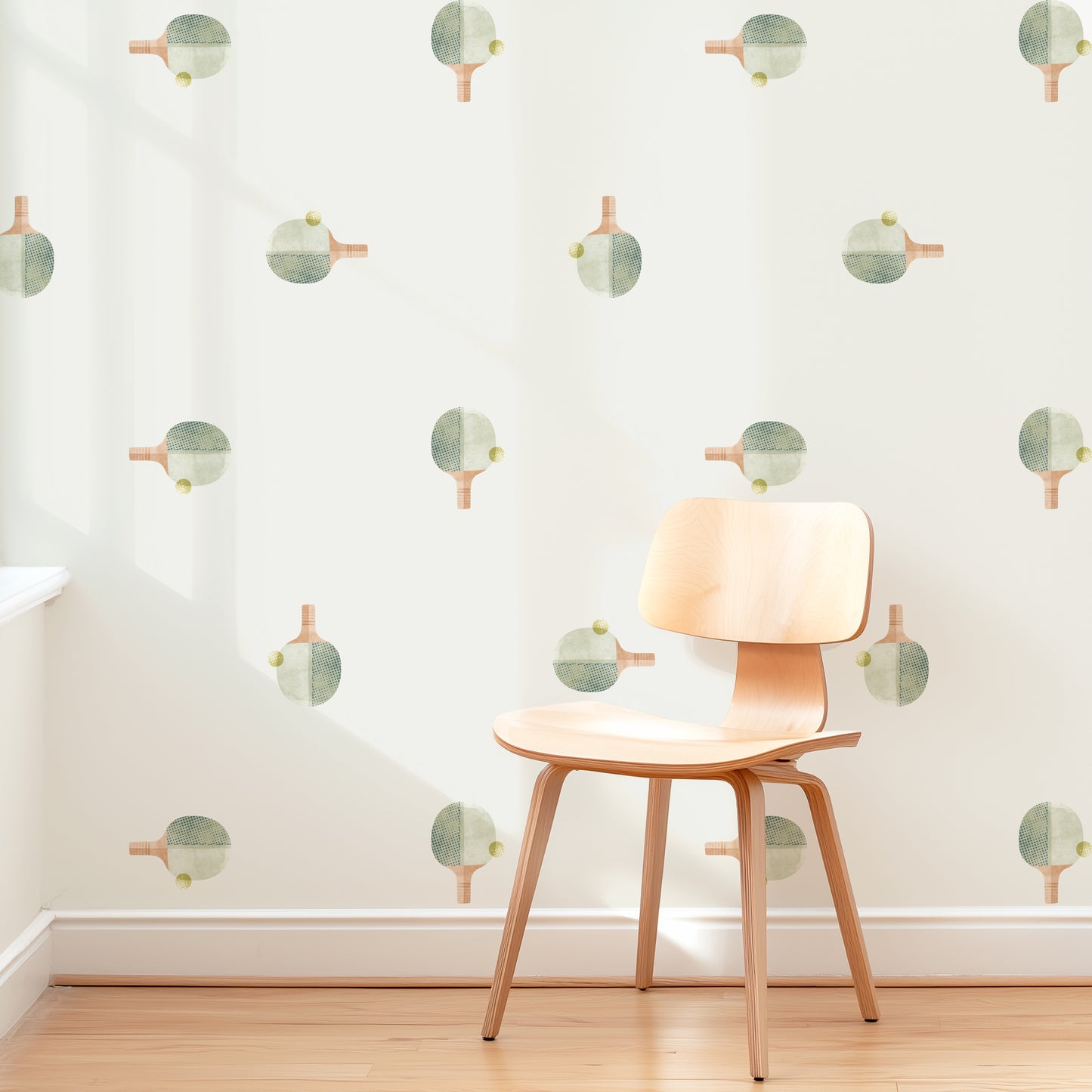 A wall is decorated with removable fabric wall decals of ping pong paddles with balls by Mej Mej. They are placed in a modern grid pattern. A mid-century chair sits in front of them for scale.