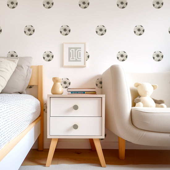 A teen room wall adorned with watercolor soccer wall decals by Mej Mej is the background for a modern chest, bed and chair. The decals are placed in an even pattern behind a small framed soccer jersey number 10.