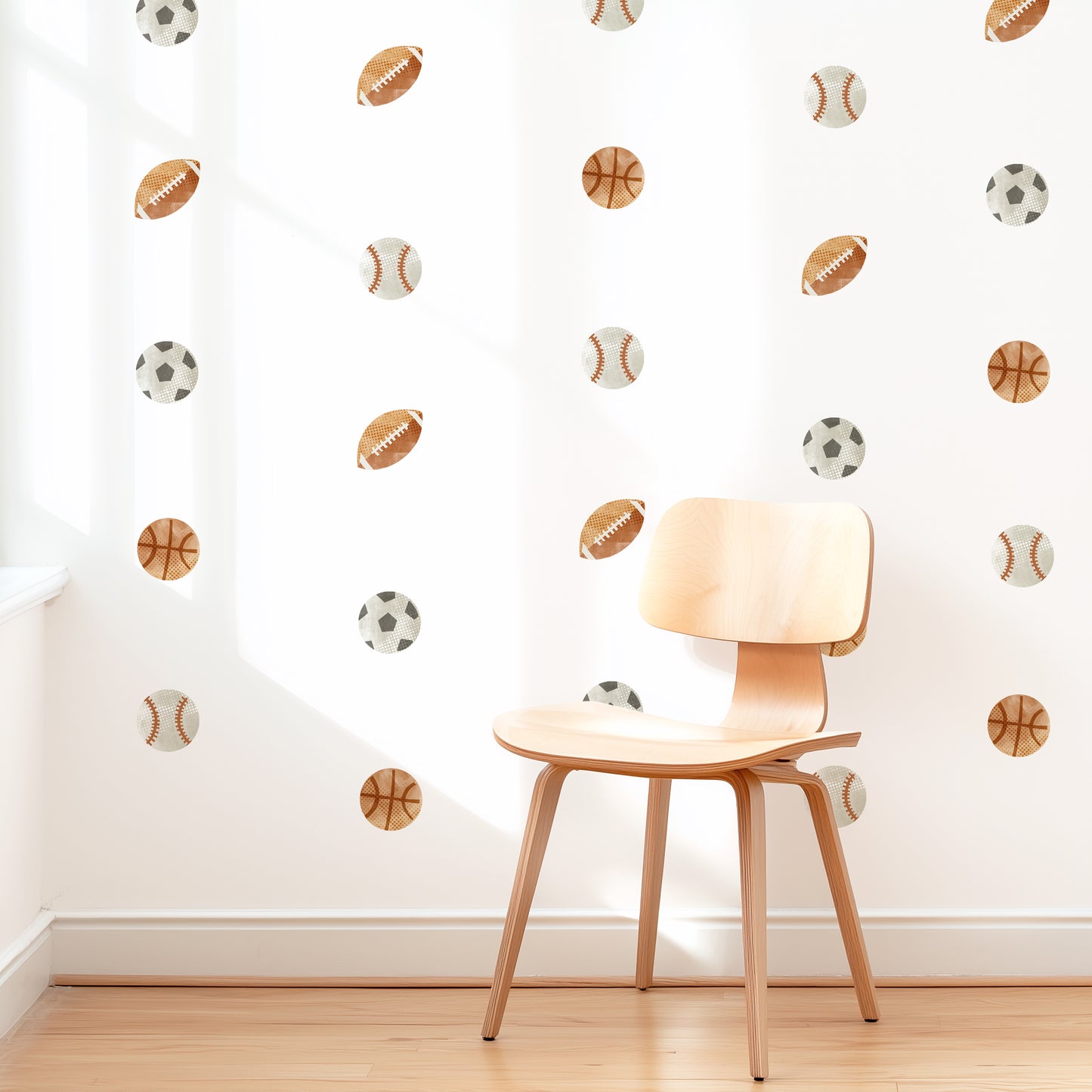 A wall is decorated with removable fabric wall decals of sports balls by Mej Mej. They are placed in a modern grid pattern. A mid-century chair sits in front of them for scale.