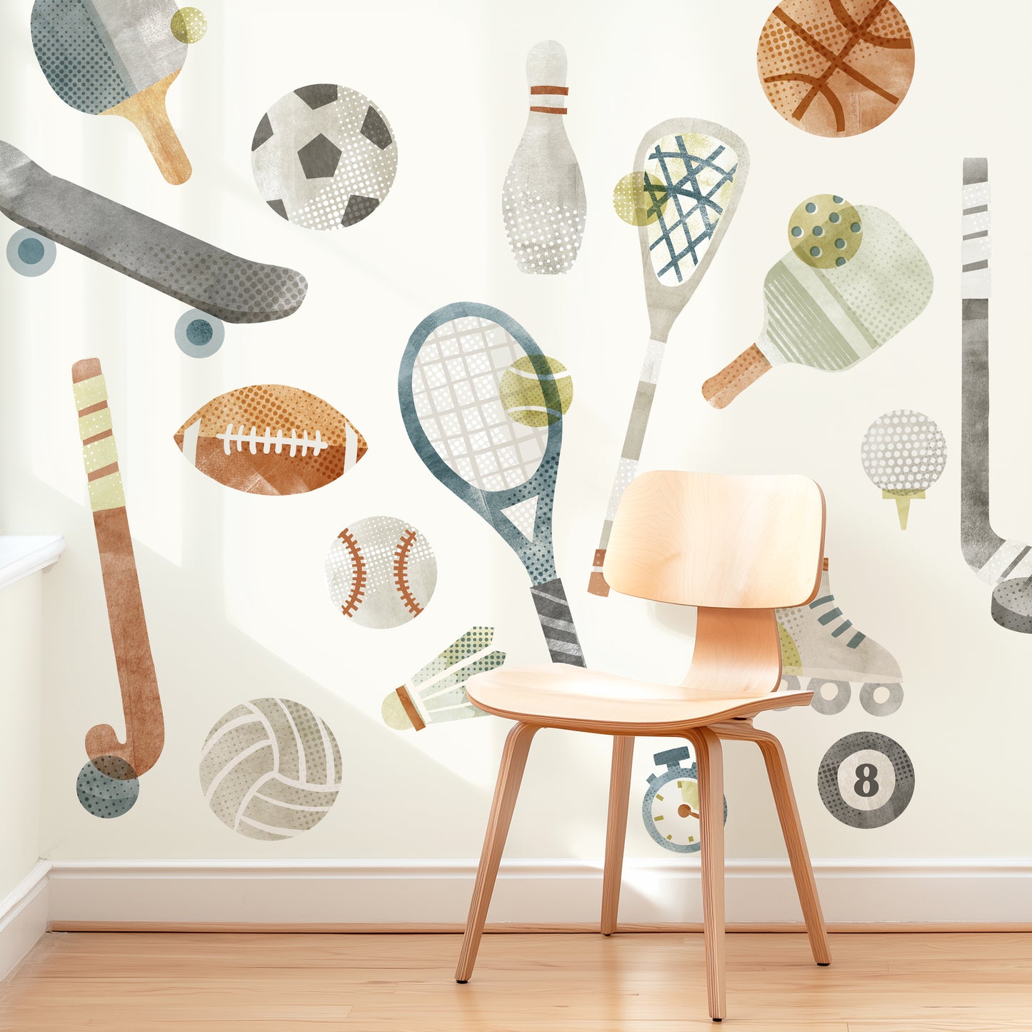 A modern space is decorated with removable fabric wall decals of all different sports equipment designed with textural watercolor artwork by Mej Mej. They are placed in an energetic toss pattern. A mid-century chair sits in front of them for scale.