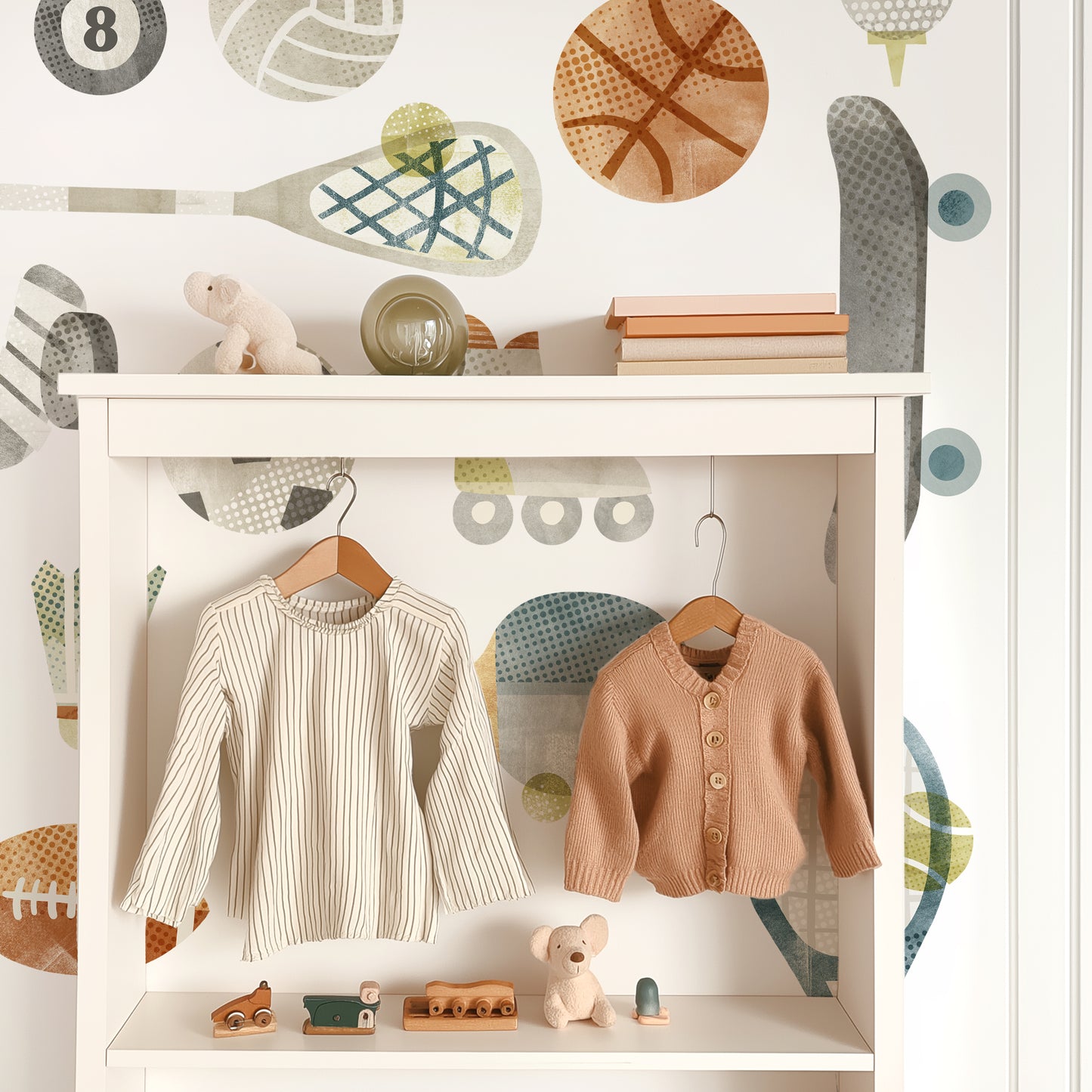 Removable fabric wall decals by Mej Mej are the backdrop for a contemporary white open-backed shelf unit with cute children’s clothes hanging on wooden hangers.