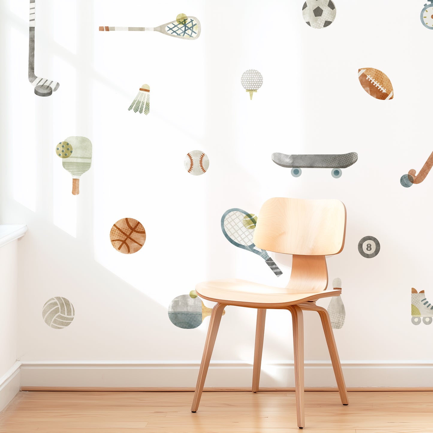 A modern space is decorated with removable fabric wall decals of all different sports equipment designed with textural watercolor artwork by Mej Mej. They are placed in an open grid pattern. A mid-century chair sits in front of them for scale.