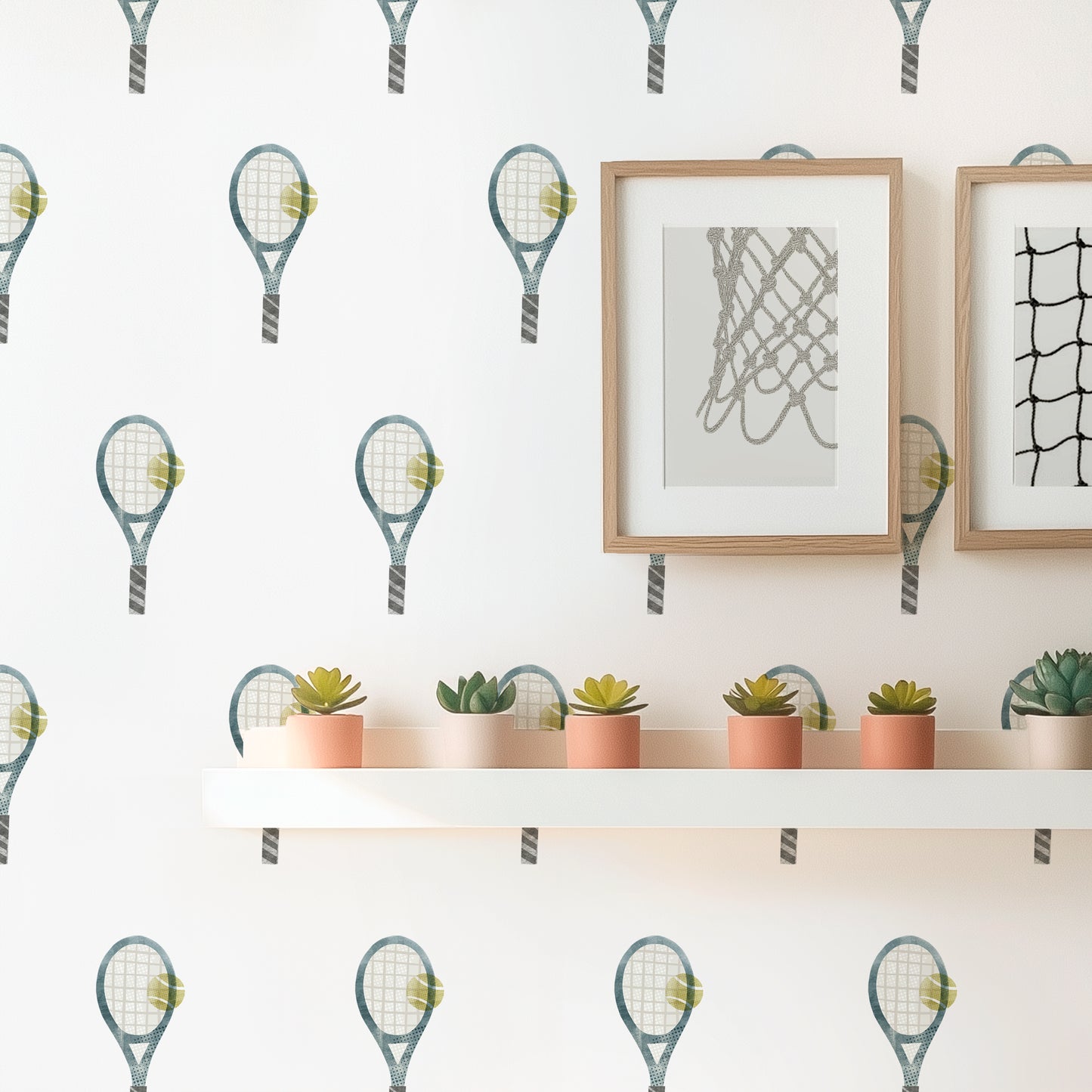 An even grid of watercolor tennis rackets wall decals by Mej Mej adorns a wall in a sunny room. A narrow shelf hangs displaying succulents.