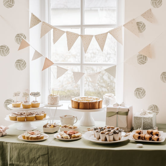 Watercolor volleyball decals by Mej Mej decorate the wall behind a tablescape of birthday treats.